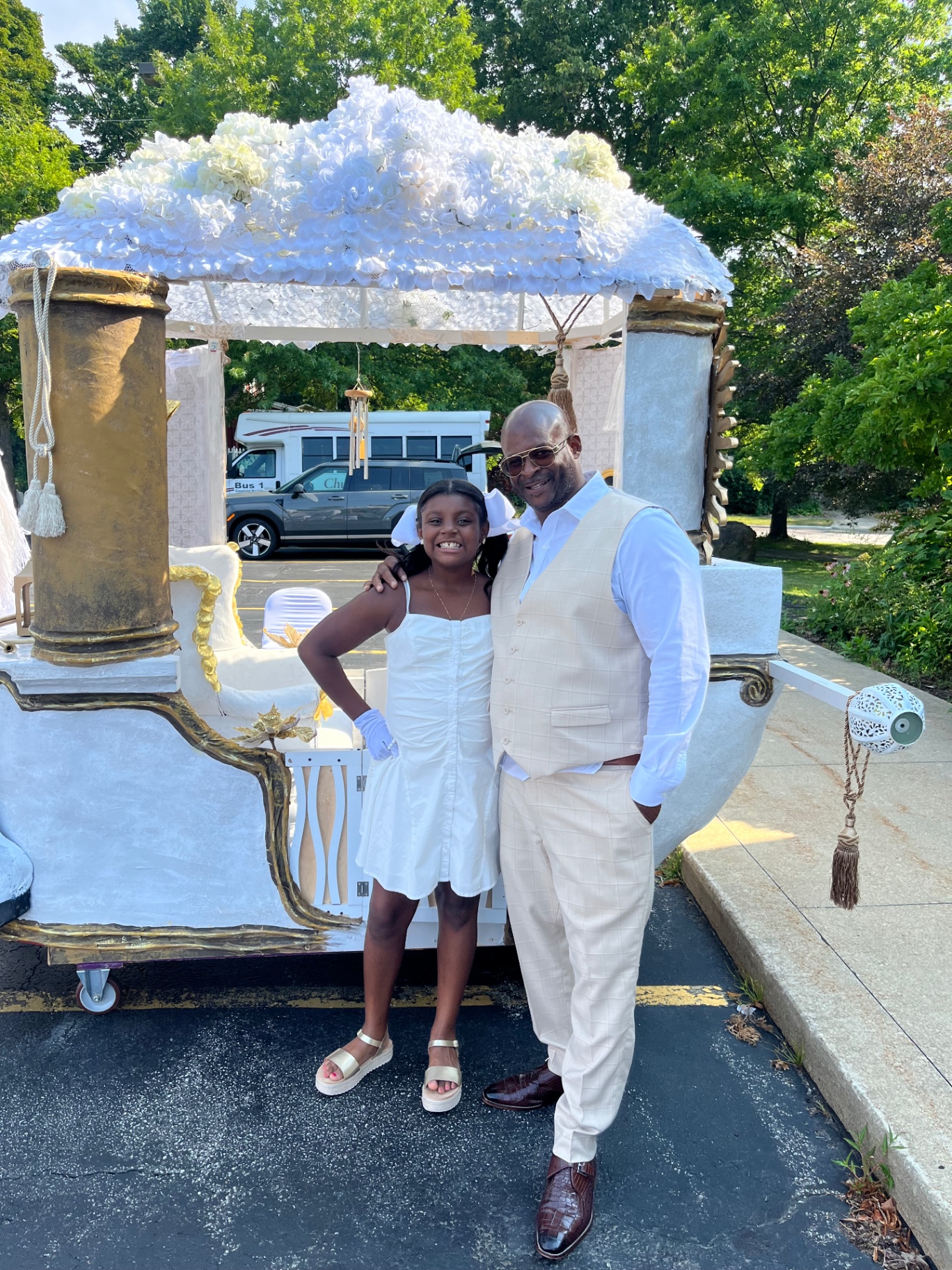 Founder and his daughter smiling in front of a decorative white carriage