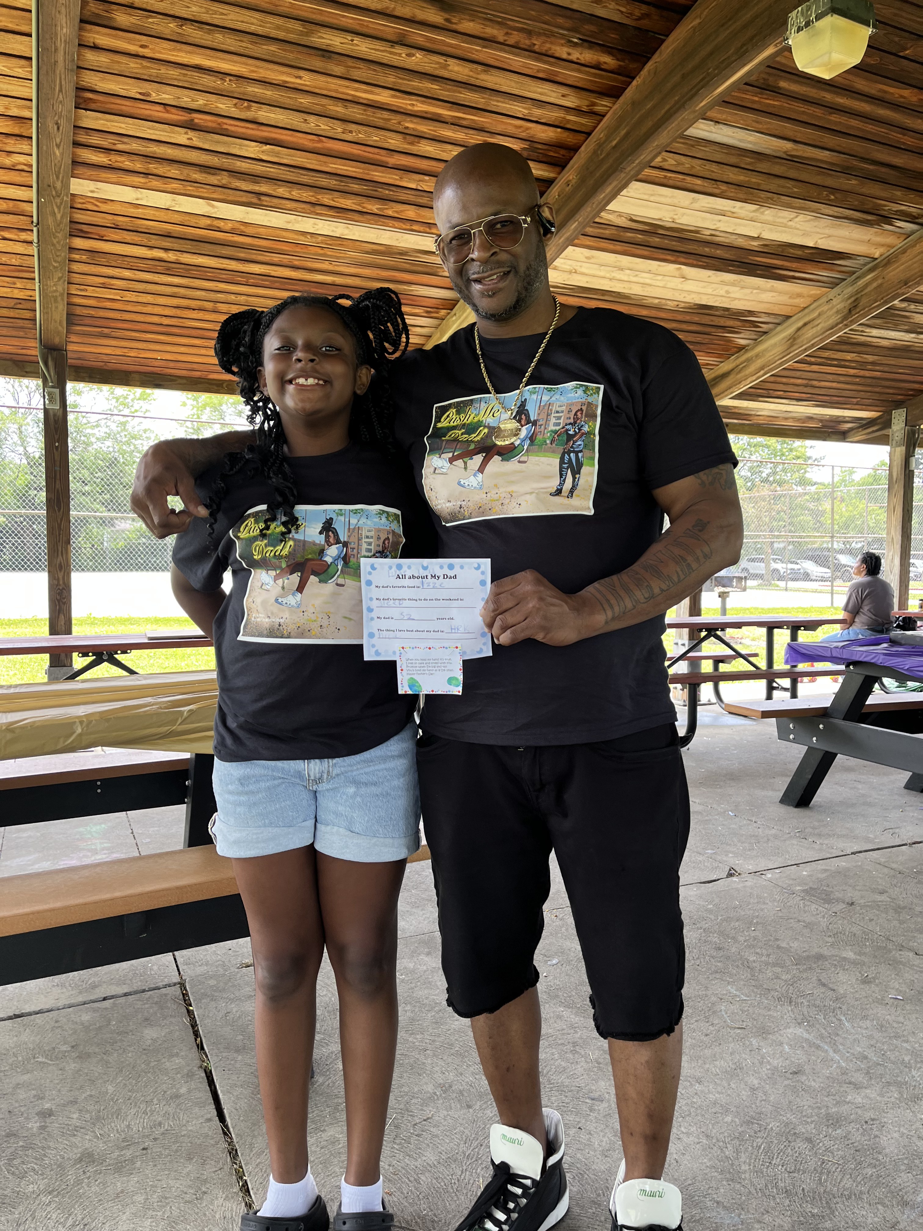 A father and daughter wearing matching Push Me Dad shirts at a community Father's Day event